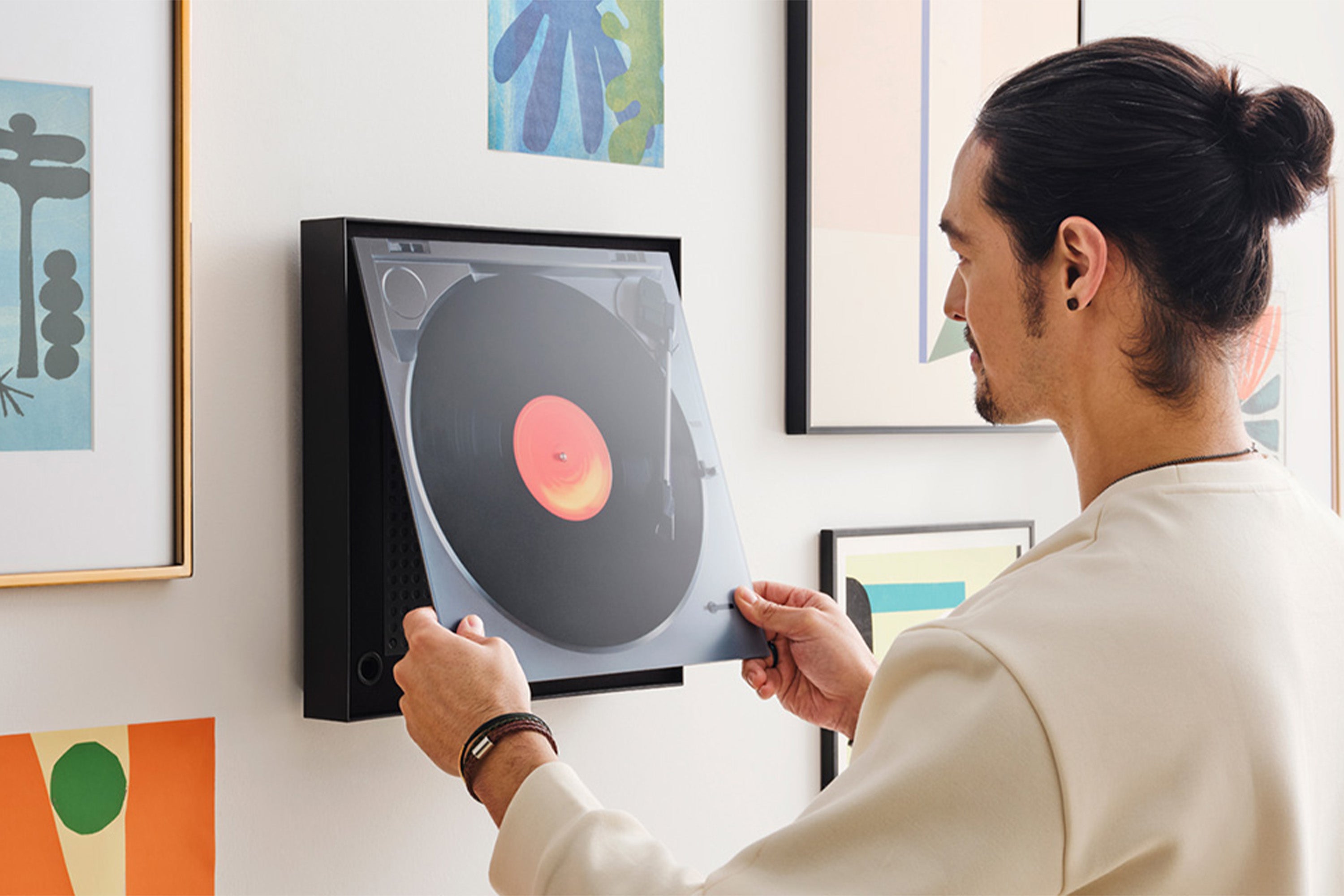 Un homme ajustant sur le mur une représentation d'un vinyle